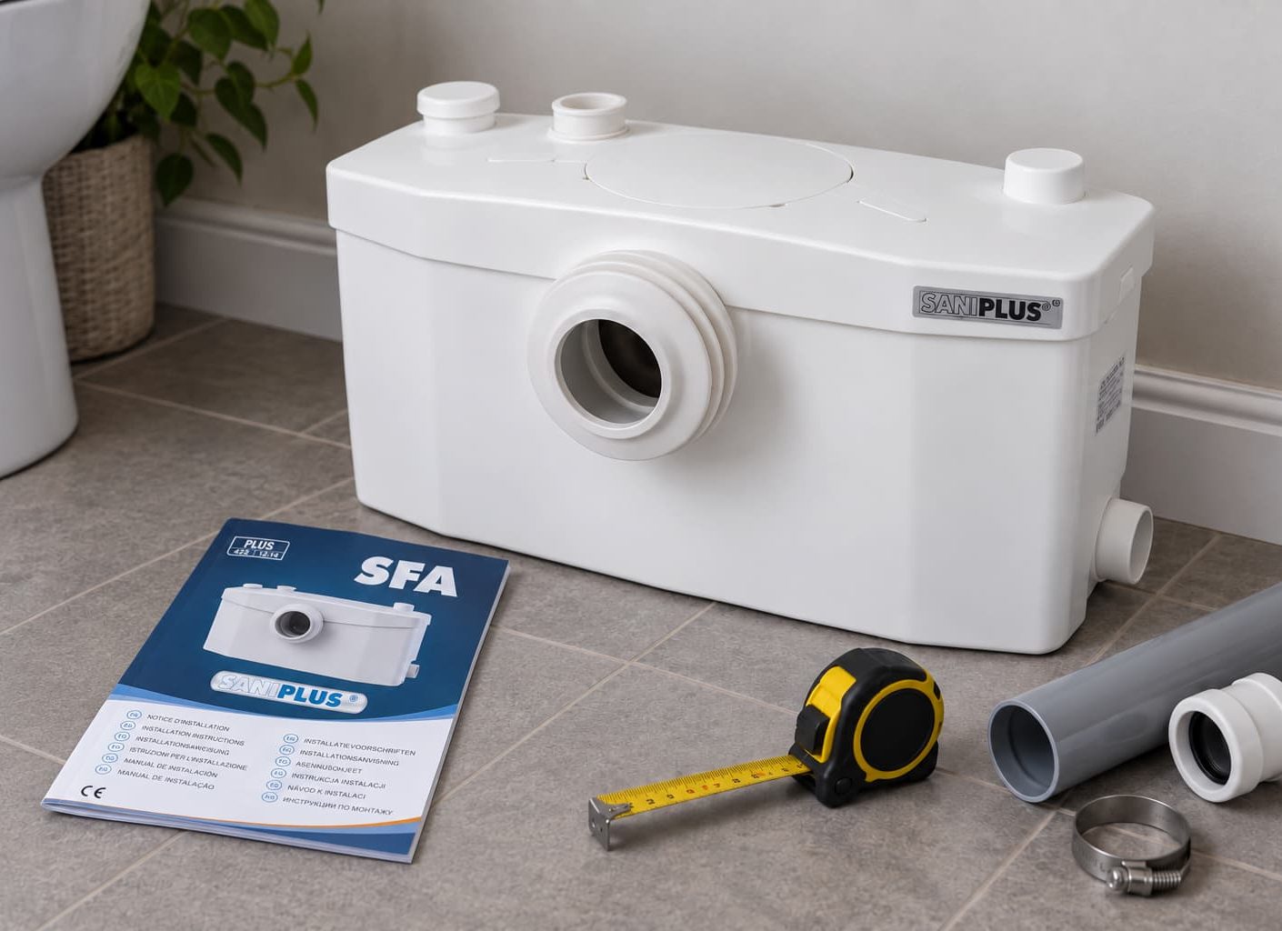 Saniflo unit with installation manual, tape measure and pipework on a bathroom floor
